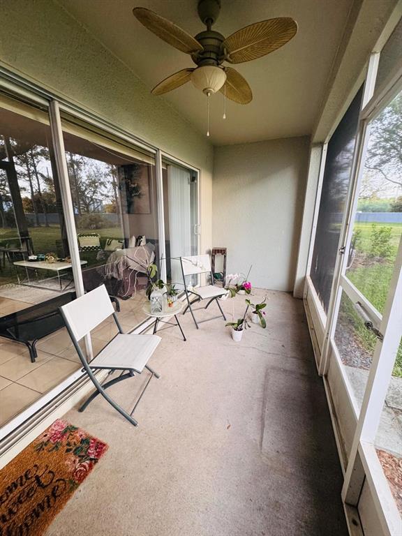 A screened-in patio features a ceiling fan, concrete flooring, and sliding glass doors — 9381 JASMINE FLOWER LANE UNIT 168, ORLANDO, FL