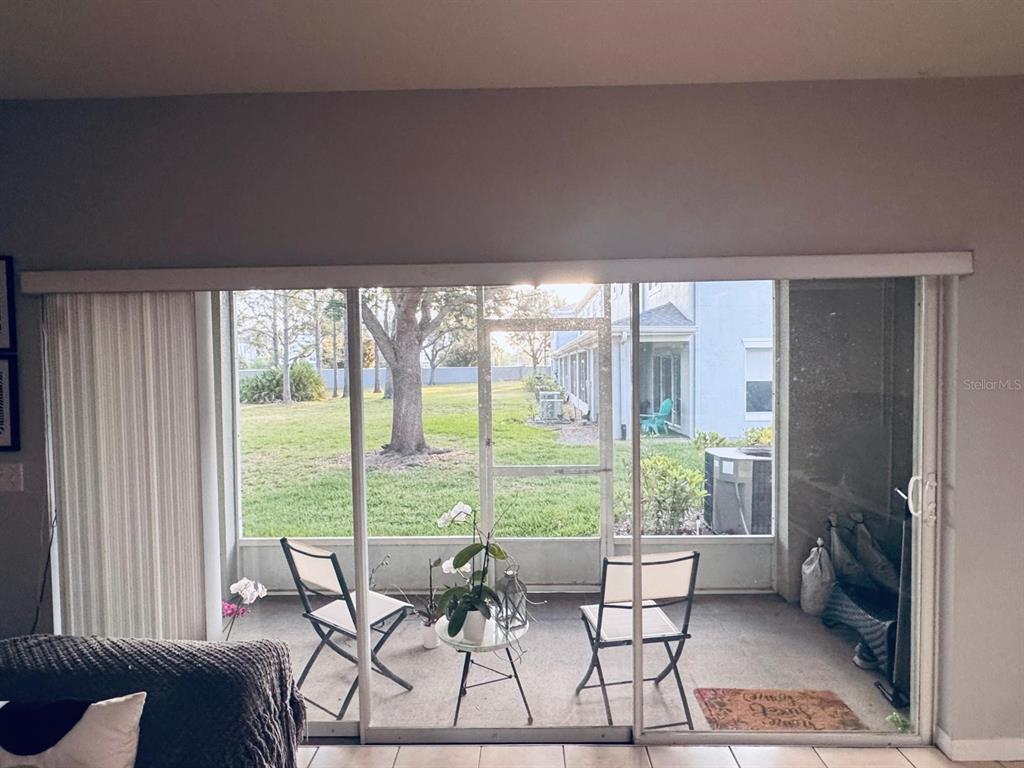 A view through sliding glass doors shows a screened-in patio with chairs and a lawn — 9381 JASMINE FLOWER LANE UNIT 168, ORLANDO, FL
