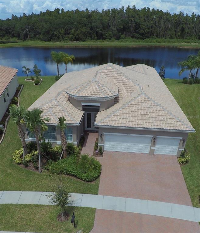 A screened-in swimming pool overlooks a lake with palm trees in the background — 16015 CAPE CORAL DRIVE, WIMAUMA, FL