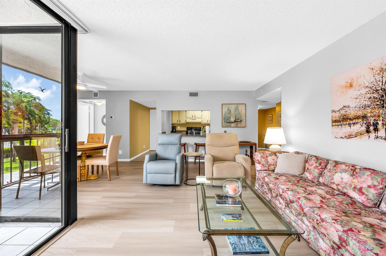 A living room with light wood floors, a floral sofa, two recliners, and a balcony view — 2255 Lindell Boulevard # 4207, Delray Beach FL 33444, DELRAY BEACH, FL