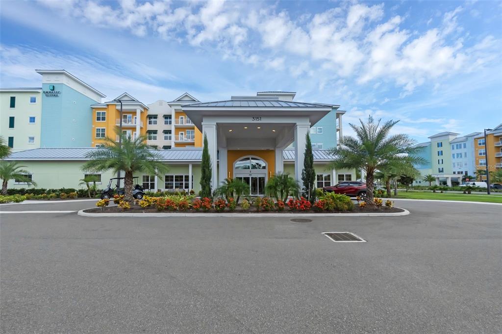 The exterior of a multi-story hotel building features a large covered entrance and palm trees — 3151 SUNSET WALK DRIVE UNIT 1108, KISSIMMEE, FL