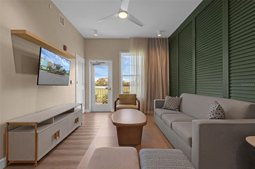 A living room features a sofa, coffee table, television, and a green louvered accent wall — 3151 SUNSET WALK DRIVE UNIT 1108, KISSIMMEE, FL