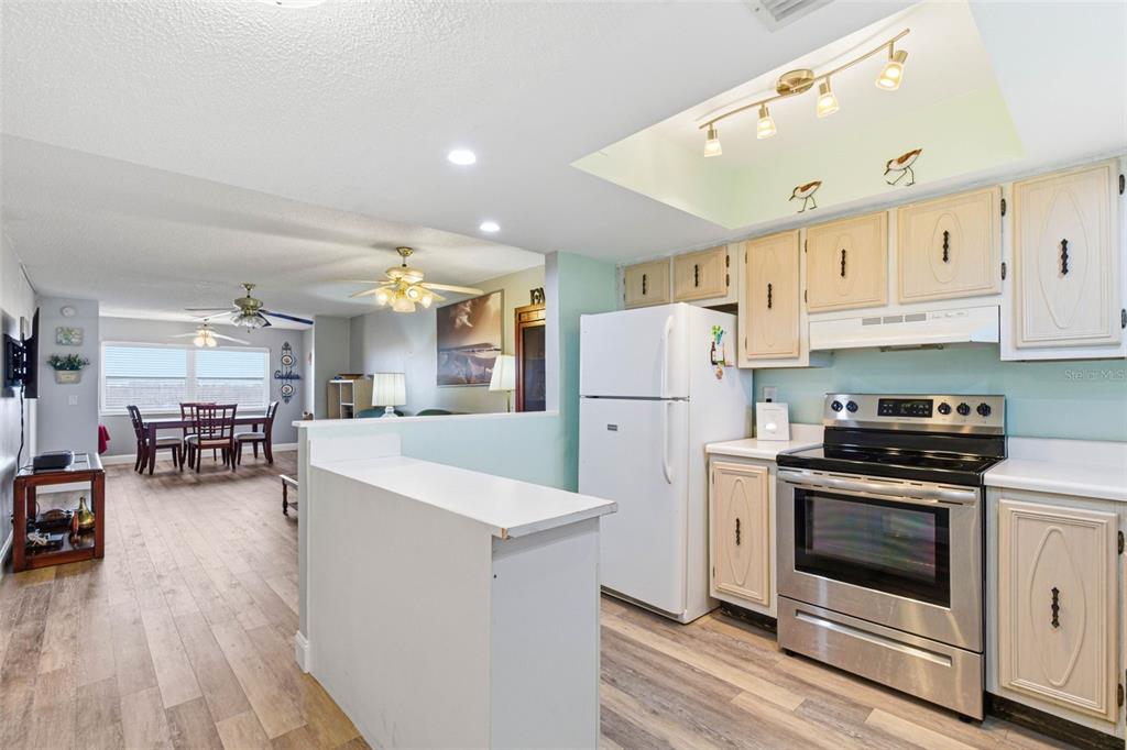 A kitchen with light wood cabinets and stainless steel appliances opens to a dining area — 801 83RD AVENUE N UNIT 510, ST PETERSBURG, FL