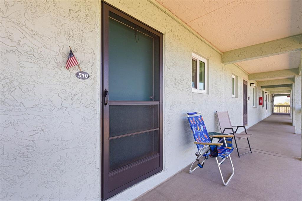 An exterior view of a building hallway featuring a door numbered 510 and two chairs — 801 83RD AVENUE N UNIT 510, ST PETERSBURG, FL
