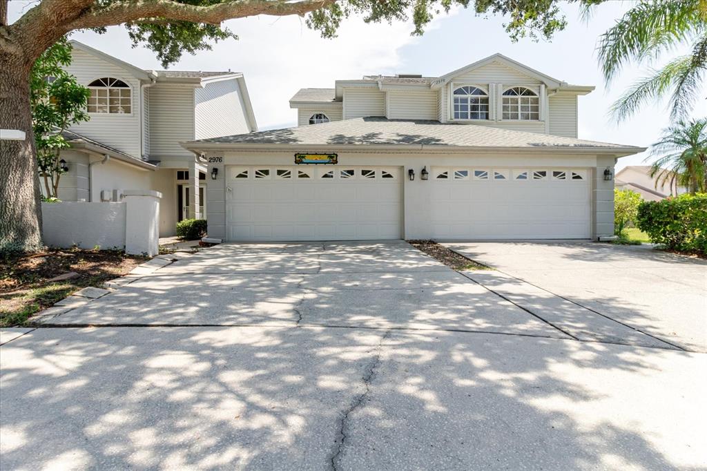 A two-story house with light siding, a three-car garage, and a concrete driveway — 2976 FIELDBROOK PLACE, CLEARWATER, FL