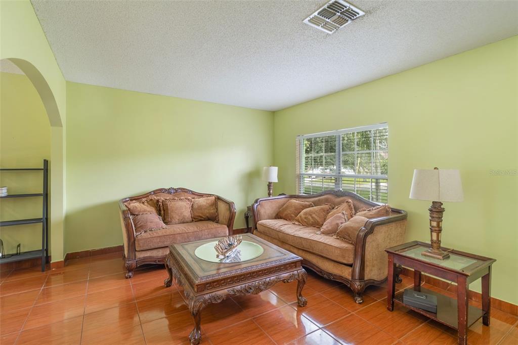 A living room features light green walls, tiled floors, two brown sofas, and a coffee table — 1139 CAMBOURNE DRIVE, KISSIMMEE, FL