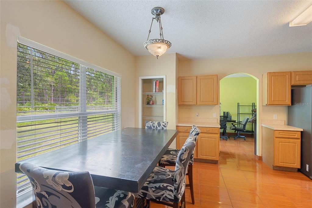 A dining area features a dark table, patterned chairs, light wood cabinets, and tile flooring — 1139 CAMBOURNE DRIVE, KISSIMMEE, FL