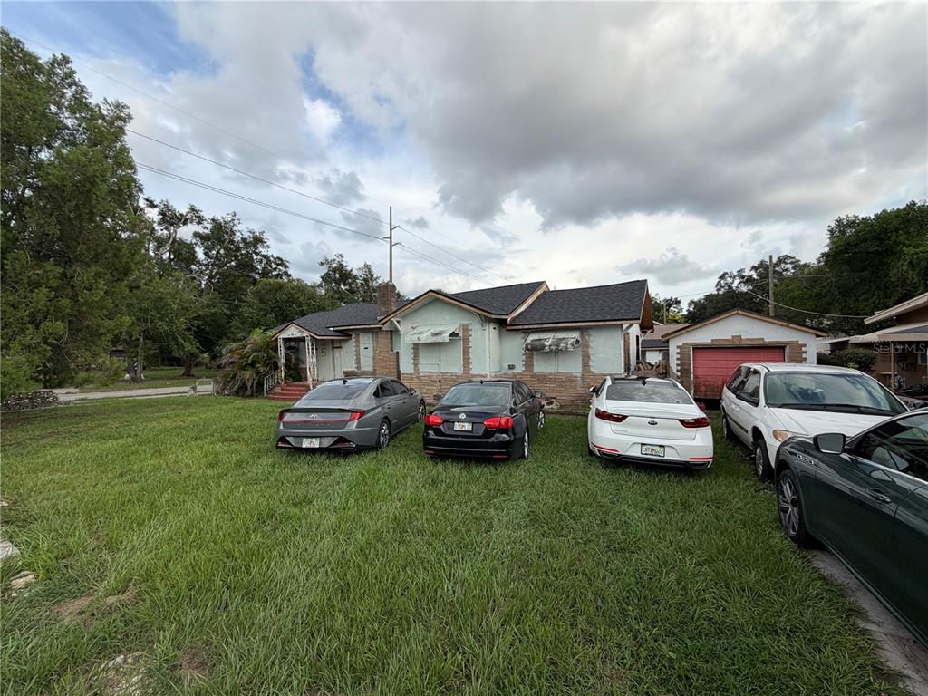 A single-story house with a detached garage and several cars parked on the front lawn — 2511 E 21ST AVENUE, TAMPA, FL