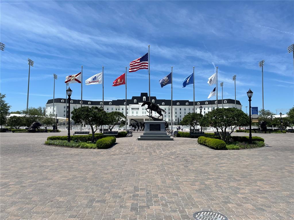 A large building stands behind a central horse statue and several flags on a plaza — 00 W HWY 40, LOT 11, OCALA, FL