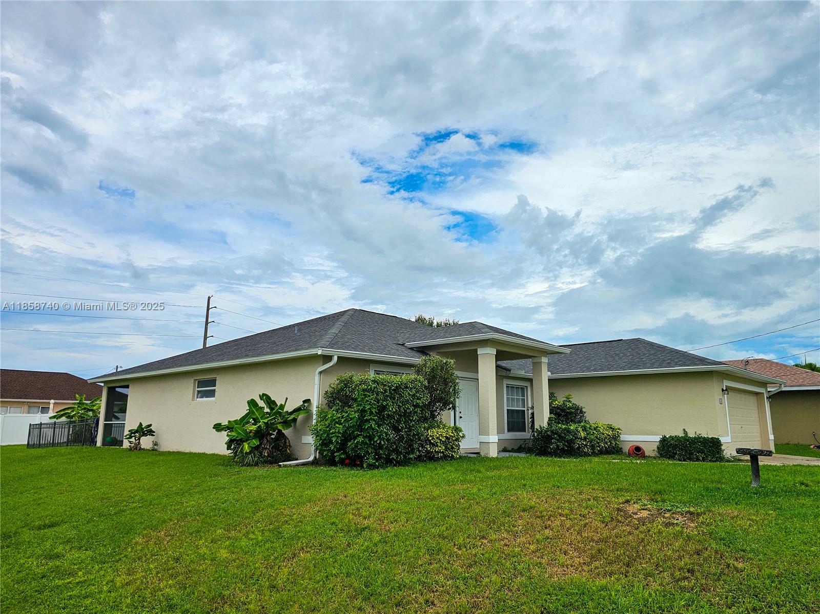 A single-story house with a beige stucco exterior, a dark shingled roof, and a front lawn — 1000 NW 24TH AVE, Cape Coral FL 33993, CAPE CORAL, FL