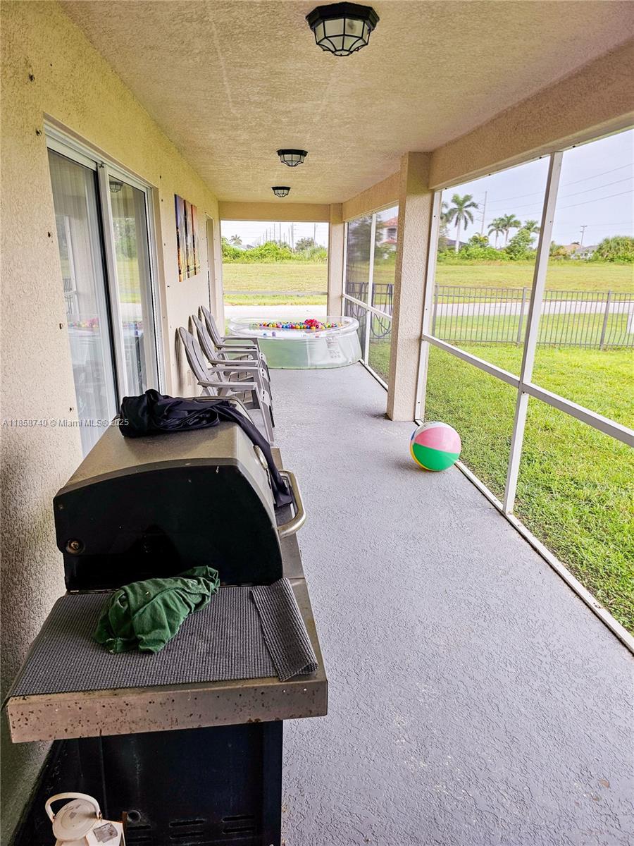 A screened-in patio features a grill, several chairs, a small pool, and a beach ball — 1000 NW 24TH AVE, Cape Coral FL 33993, CAPE CORAL, FL