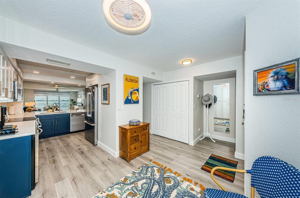 A kitchen with blue cabinets and wood-look flooring opens into a hallway with a closet — 6105 BAHIA DEL MAR CIRCLE UNIT 287, ST PETERSBURG, FL