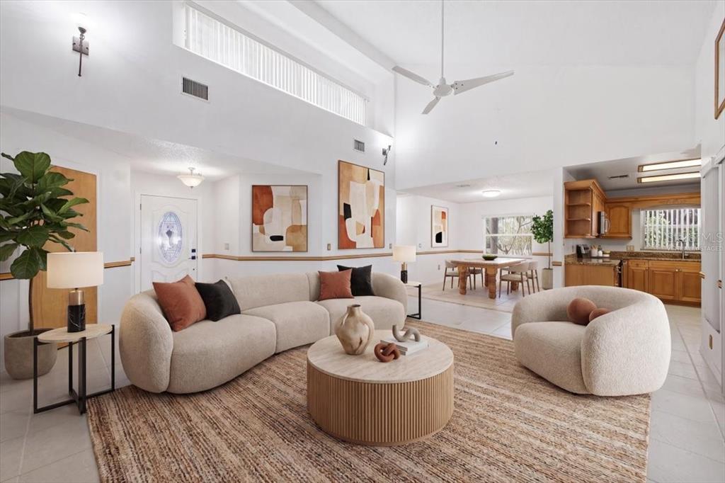 A bright living room features a curved sofa, round coffee table, and an open kitchen — 720 50TH STREET E, BRADENTON, FL