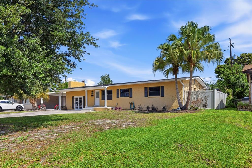 A yellow single-story house with a palm tree and a driveway under a blue sky — 3707 PELICAN LANE, ORLANDO, FL