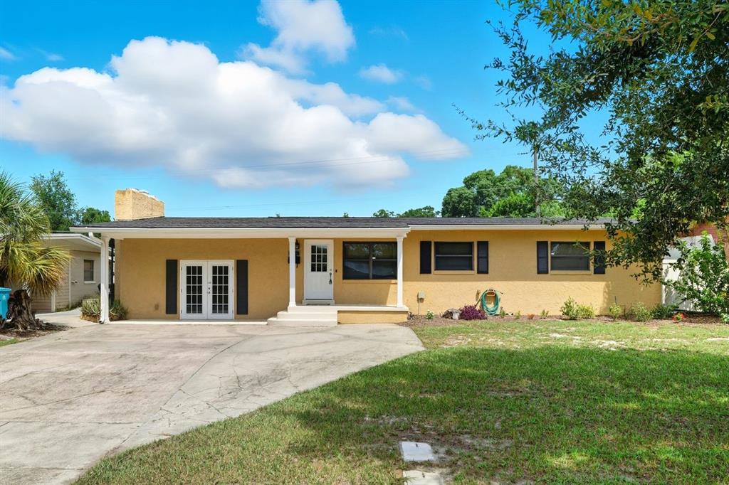 A single-story yellow house with a concrete driveway, white front door, and black shutters — 3707 PELICAN LANE, ORLANDO, FL