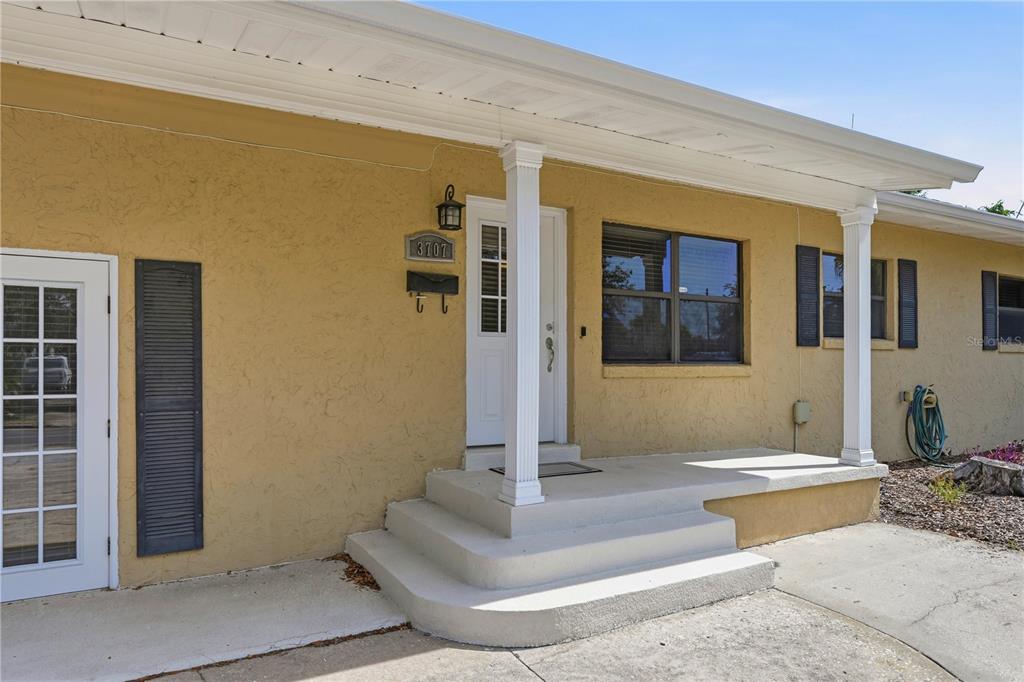 The exterior of a tan house features a covered porch with white columns and steps — 3707 PELICAN LANE, ORLANDO, FL