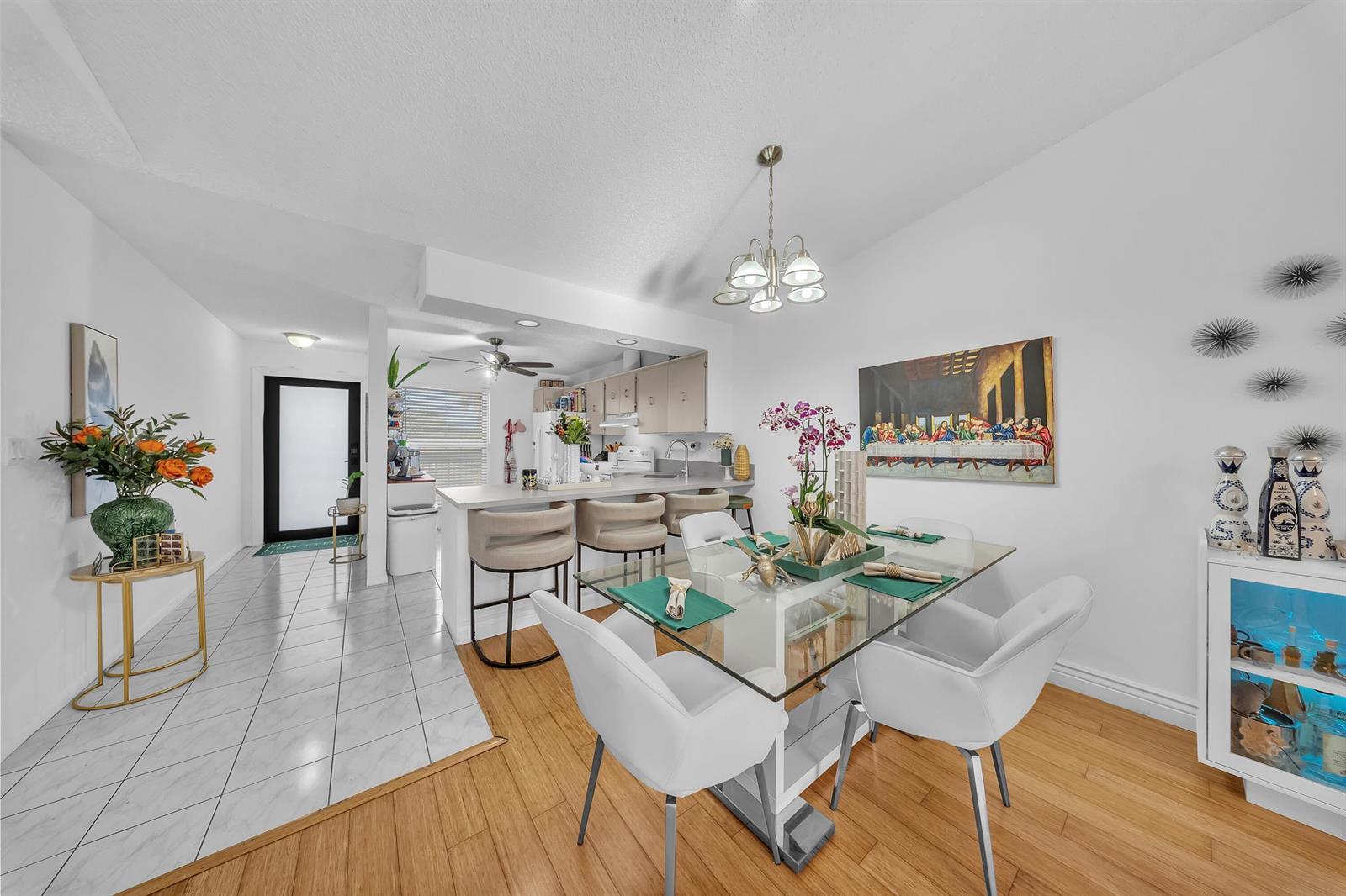A dining area with a glass table and white chairs sits adjacent to a kitchen — 1023 Banks Road # 201, Margate FL 33063, MARGATE, FL