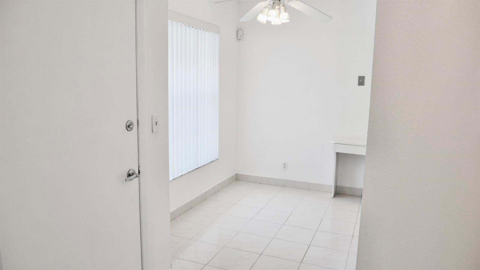 A small, white-walled room features a tiled floor, a ceiling fan, and a window — 13638 Via Flora # D, Delray Beach FL 33484, DELRAY BEACH, FL