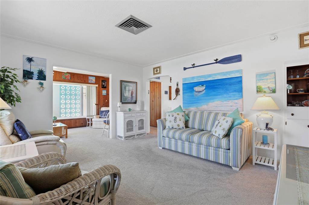 A living room features a striped sofa, wicker chairs, and coastal-themed wall art — 2101 JO AN DRIVE, SARASOTA, FL