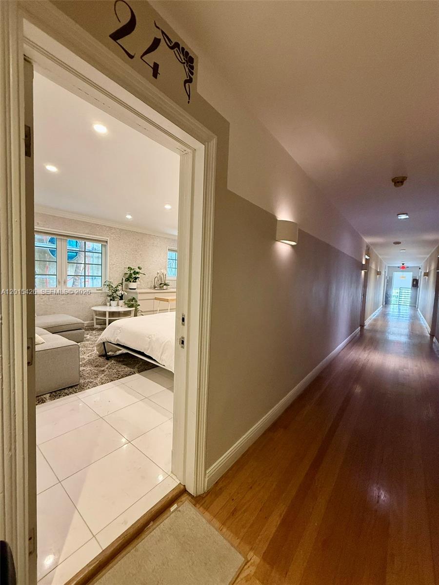 A hallway with hardwood floors leads to a bedroom featuring white tile flooring — 260 Euclid Ave # 24, Miami Beach FL 33139, MIAMI BEACH, FL