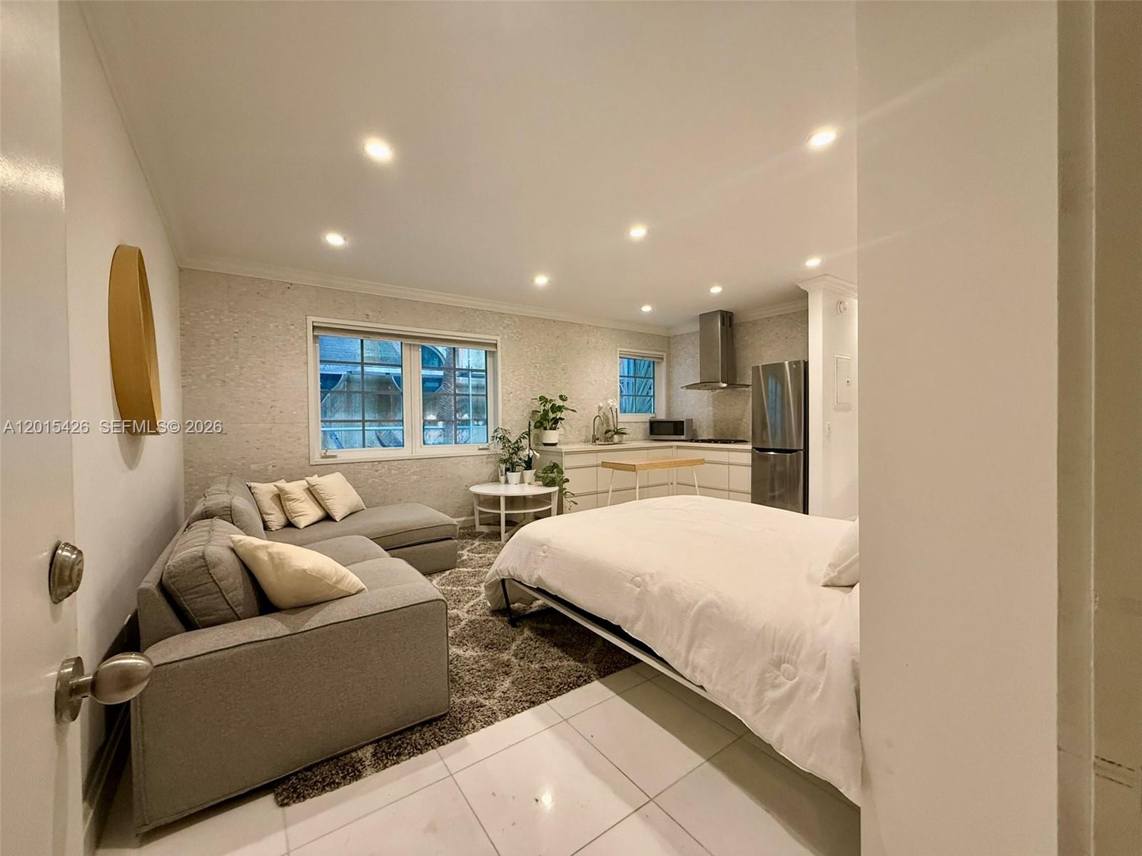 A studio apartment features a gray sofa, a bed, and a kitchen with stainless appliances — 260 Euclid Ave # 24, Miami Beach FL 33139, MIAMI BEACH, FL