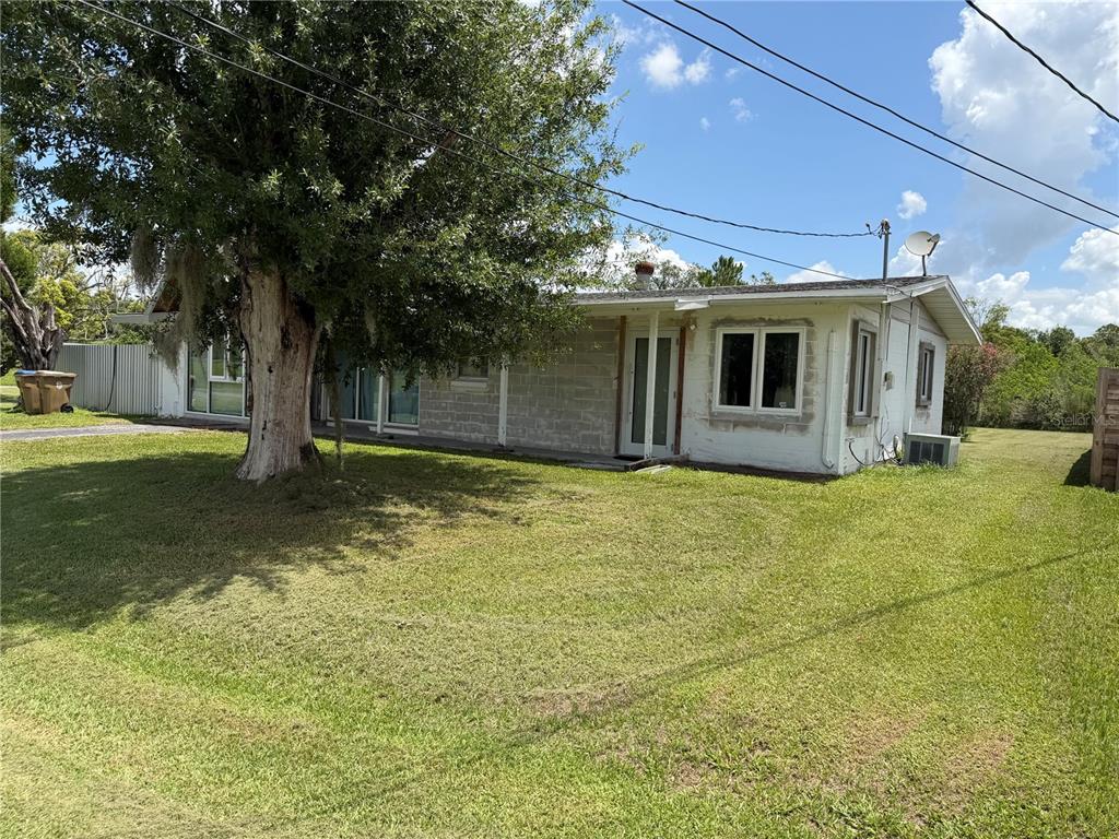 A side view of a white concrete block house with an open window and porch — 1315 S SHORE DRIVE, ST CLOUD, FL