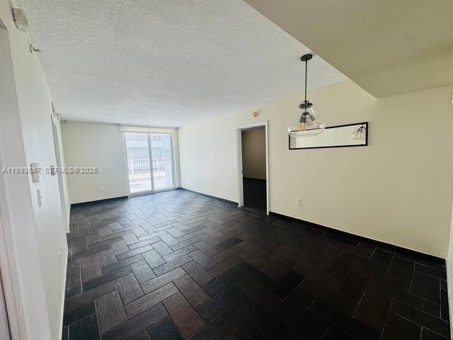An empty room features dark herringbone-patterned tile flooring, a hanging pendant light, and sliding doors — 7800 Collins Ave # 203, Miami Beach FL 33141, MIAMI BEACH, FL