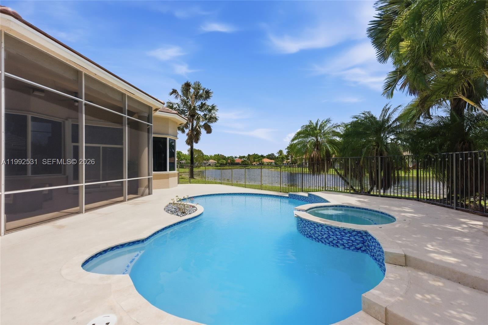 A backyard swimming pool and attached spa sit on a patio overlooking a lake — 2488 Provence Cir, Weston FL 33327, WESTON, FL