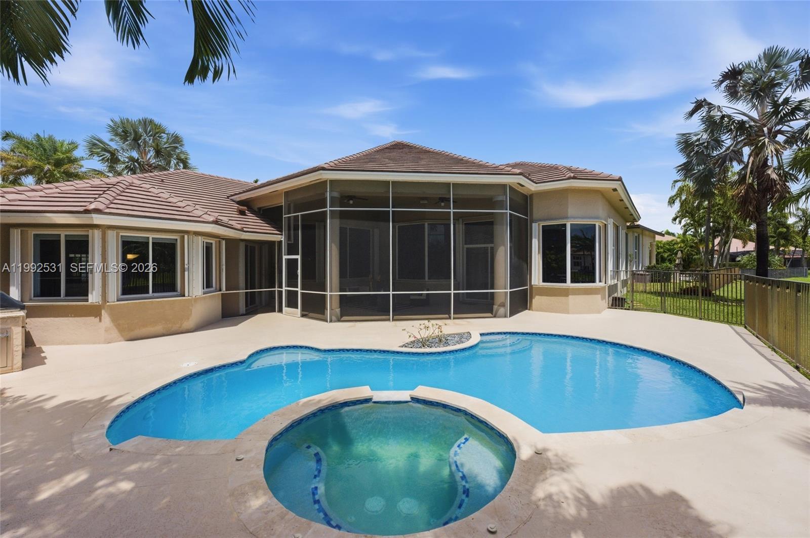 A backyard features a swimming pool with an attached spa and a screened-in patio area — 2488 Provence Cir, Weston FL 33327, WESTON, FL