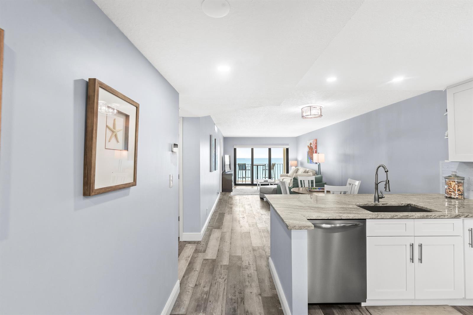 A kitchen with granite countertops and stainless steel appliances overlooks a living area with ocean views — 9490 S Ocean Drive Apt 710, Jensen Beach FL 34957, JENSEN BEACH, FL