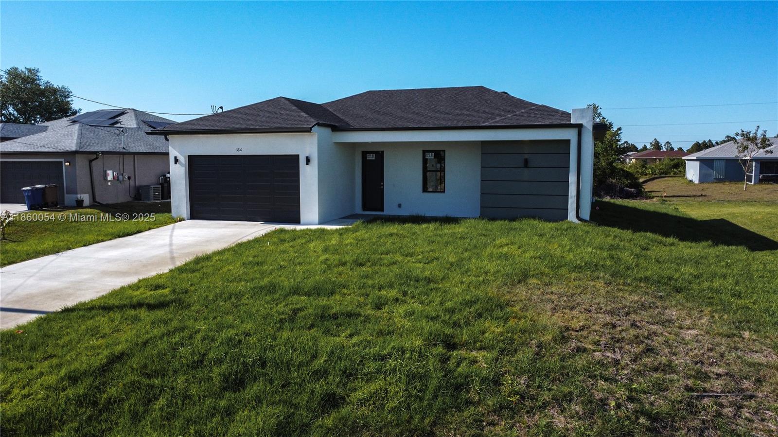 A single-story house with a white exterior, dark garage door, and a front lawn — 3610 SW 22ND ST, Lehigh Acres FL 33976, LEHIGH ACRES, FL