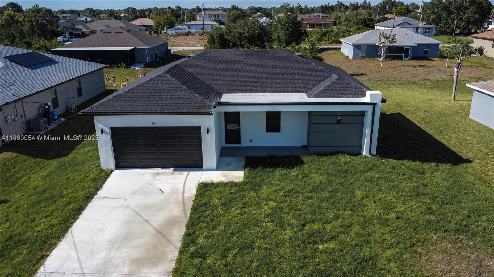 An aerial view shows a single-story house with a dark roof, white walls, and a driveway — 3610 SW 22ND ST, Lehigh Acres FL 33976, LEHIGH ACRES, FL