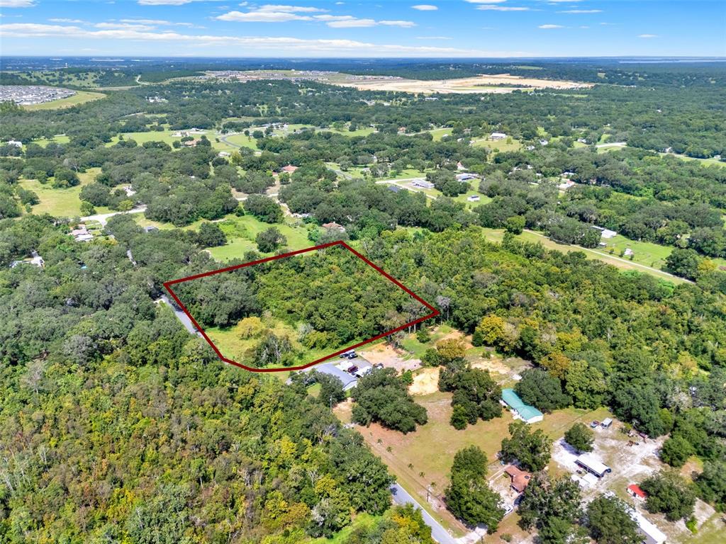 An aerial view shows a rectangular plot of land outlined in red amidst wooded terrain — 15325 TROUSDALE STREET, CLERMONT, FL