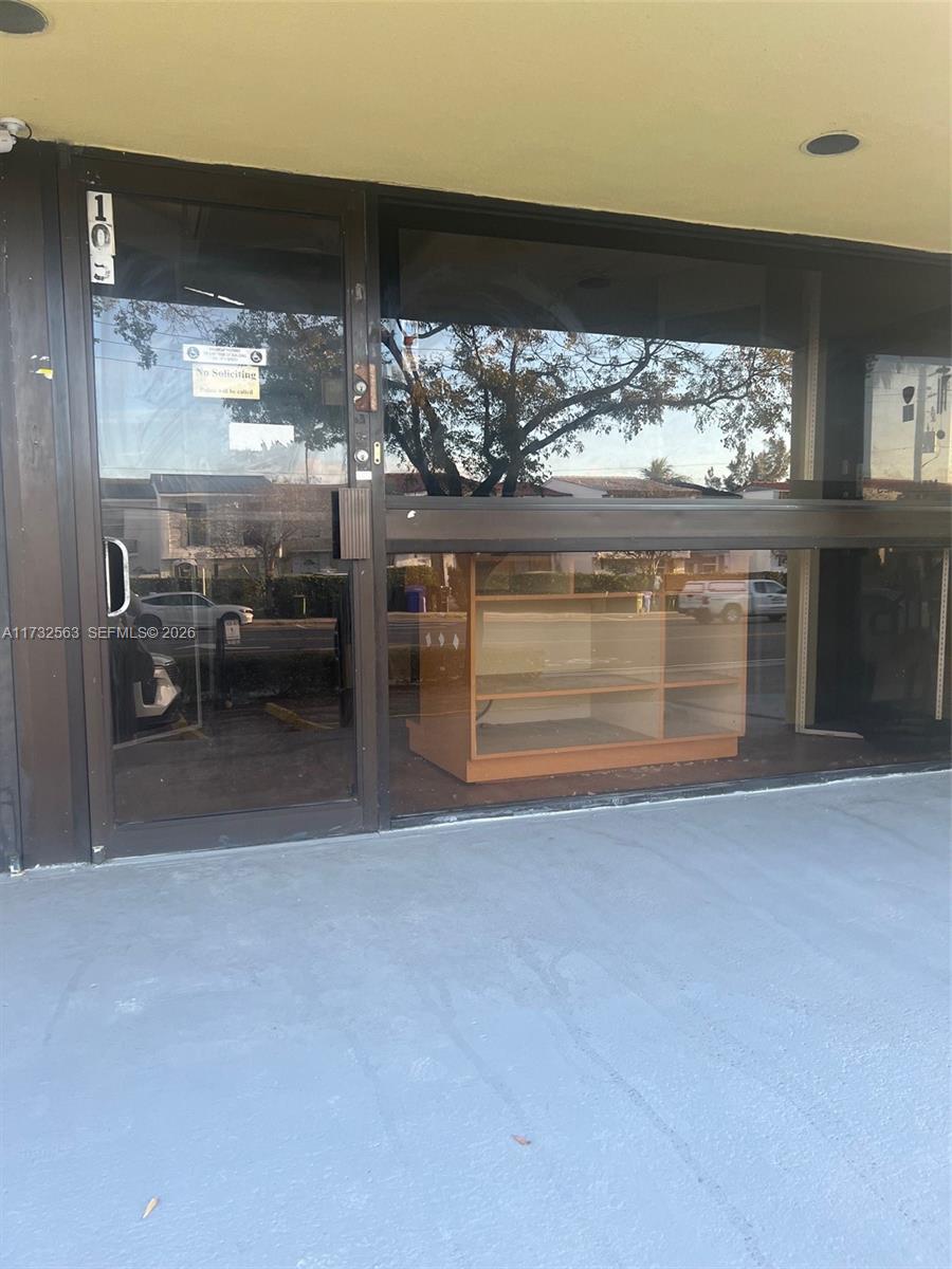The exterior view shows a glass storefront door and window with a wooden display shelf inside — 1948 NE 123rd St # 105, North Miami FL 33181, NORTH MIAMI, FL