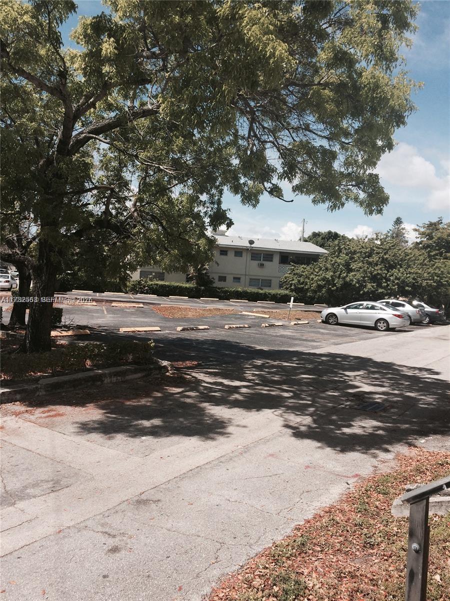 An outdoor parking lot with several parked cars sits in front of a multi-story building — 1948 NE 123rd St # 105, North Miami FL 33181, NORTH MIAMI, FL