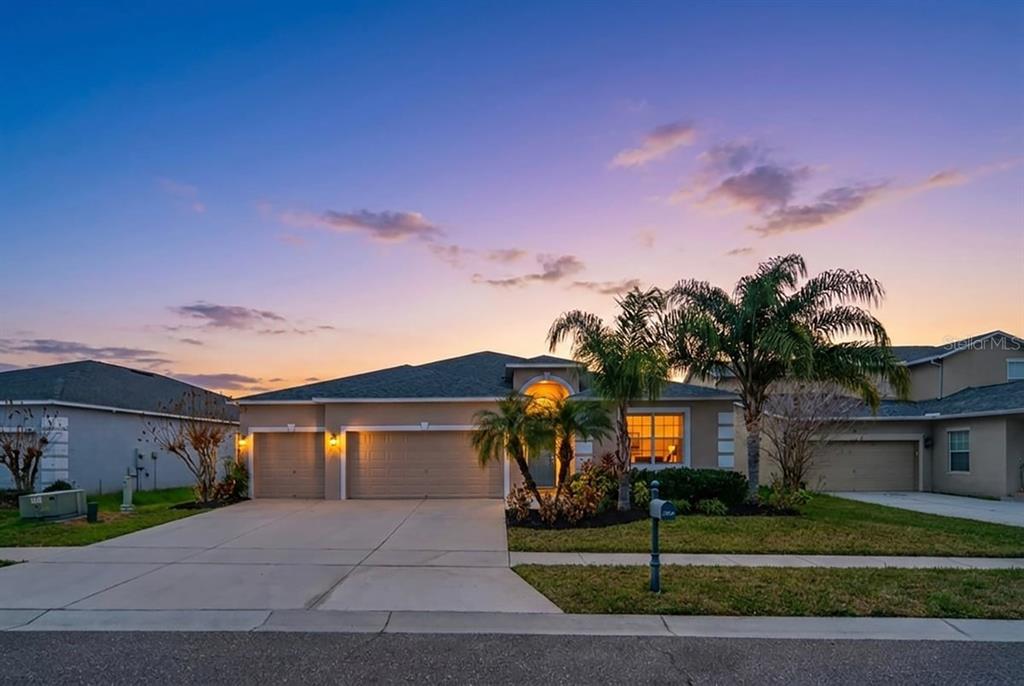 A single-story suburban house with a three-car garage and palm trees at sunset — 2854 YOUNGFORD STREET, ORLANDO, FL