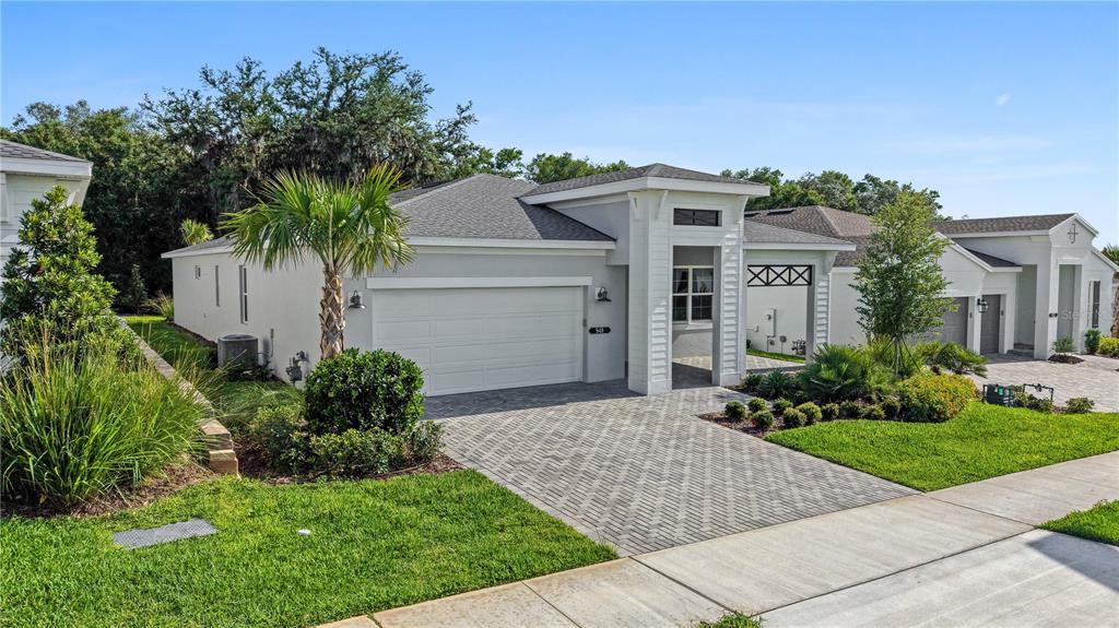 A modern single-story house with a white exterior, a two-car garage, and a paved driveway — 948 CLUB CRESSWIND DRIVE, LADY LAKE, FL