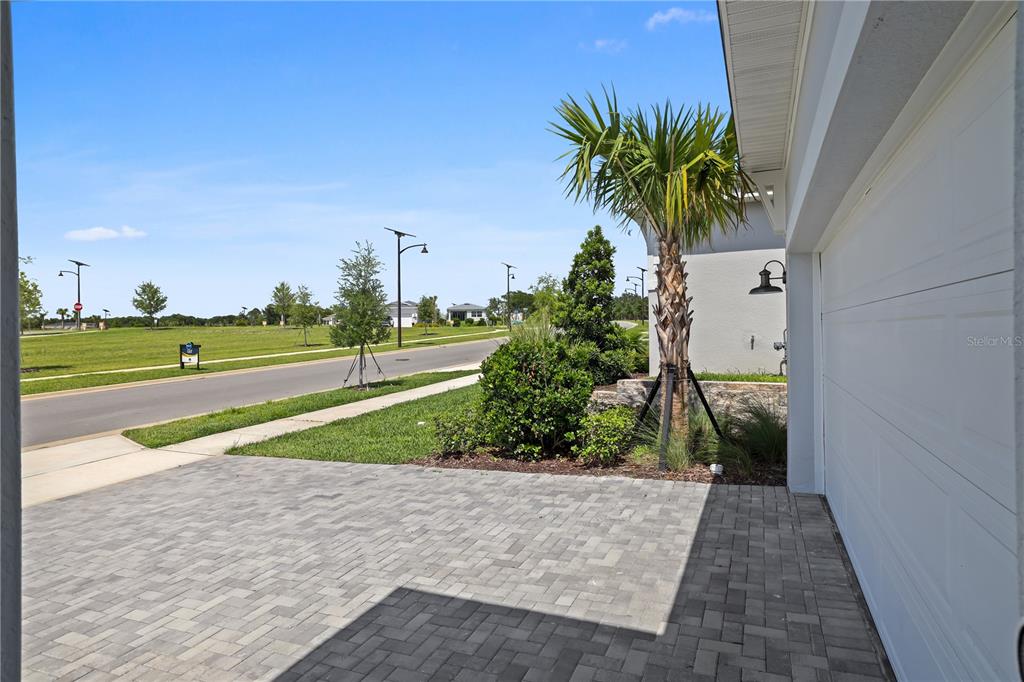 A paved driveway leads to a garage next to a palm tree and landscaped yard — 948 CLUB CRESSWIND DRIVE, LADY LAKE, FL
