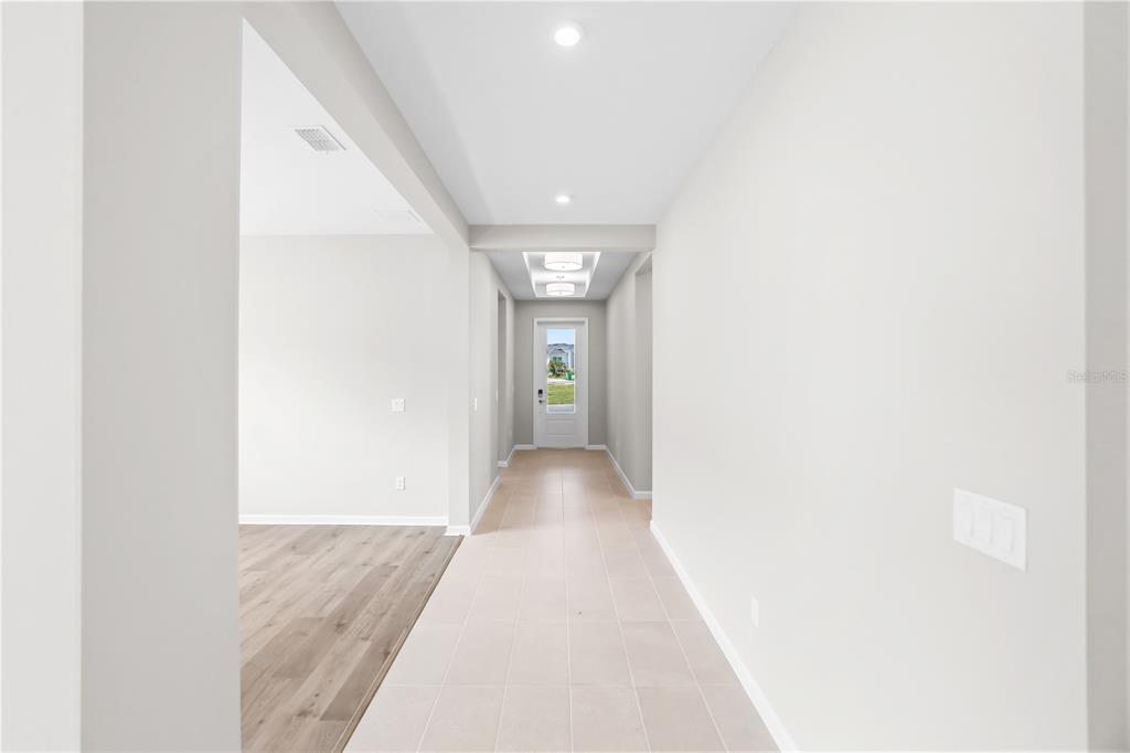 A hallway with light tile flooring leads to a white front door with glass panels — 948 CLUB CRESSWIND DRIVE, LADY LAKE, FL
