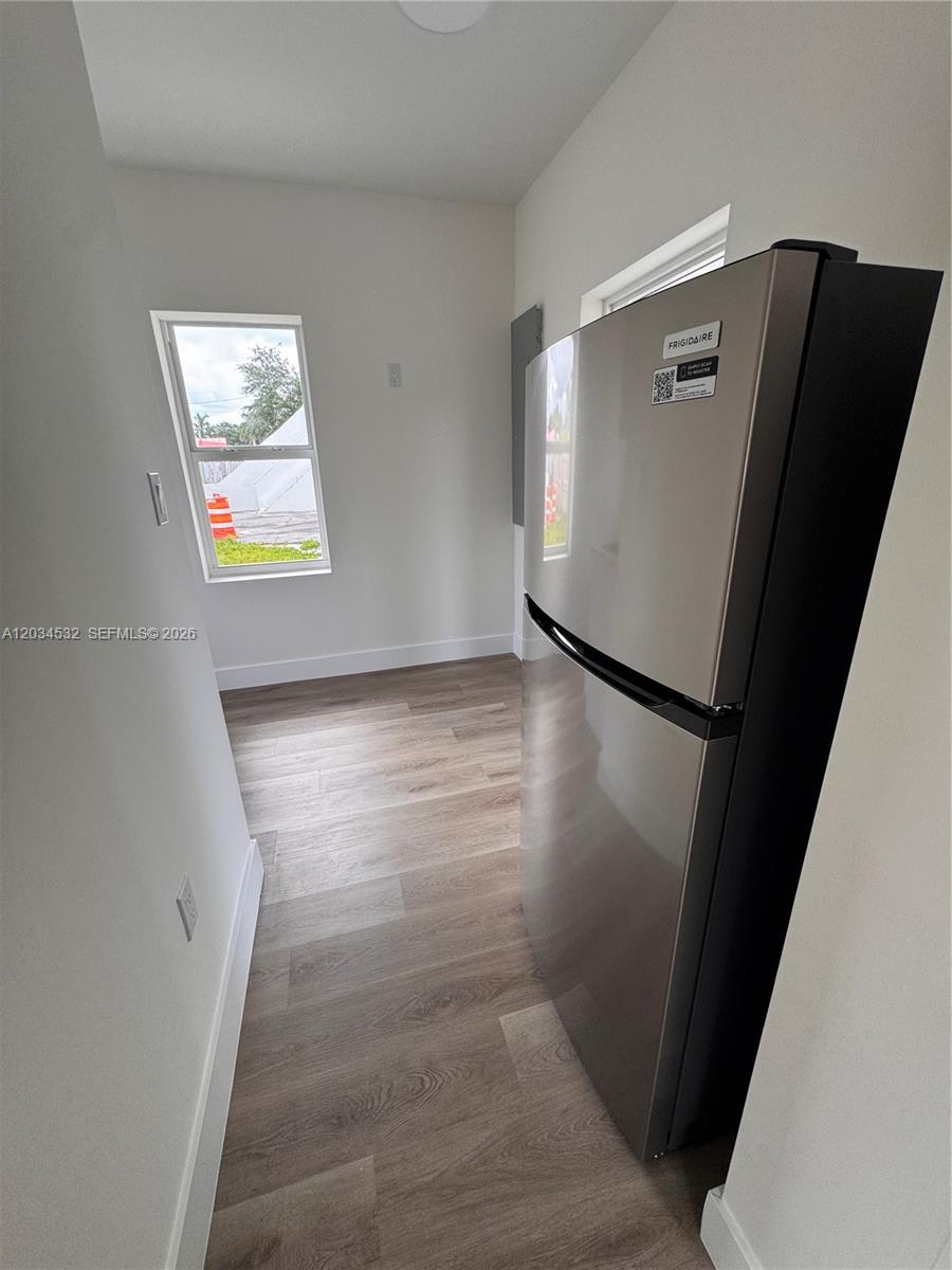 A kitchen area features light wood-look flooring, white walls, a window, and a stainless refrigerator — 2239 NW 87th St # 8, Miami FL 33147, MIAMI, FL
