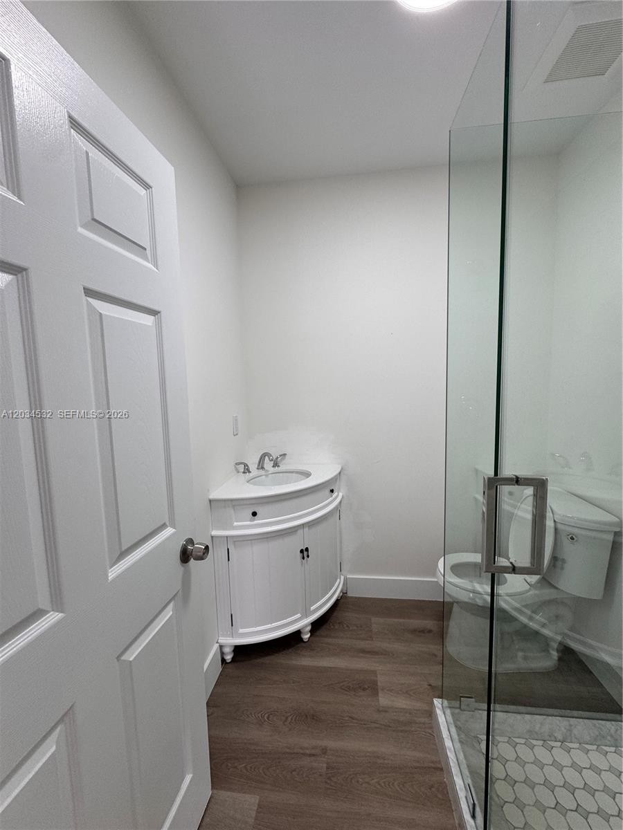 A small bathroom features a corner vanity, a glass-enclosed shower, and wood-look flooring — 2239 NW 87th St # 8, Miami FL 33147, MIAMI, FL