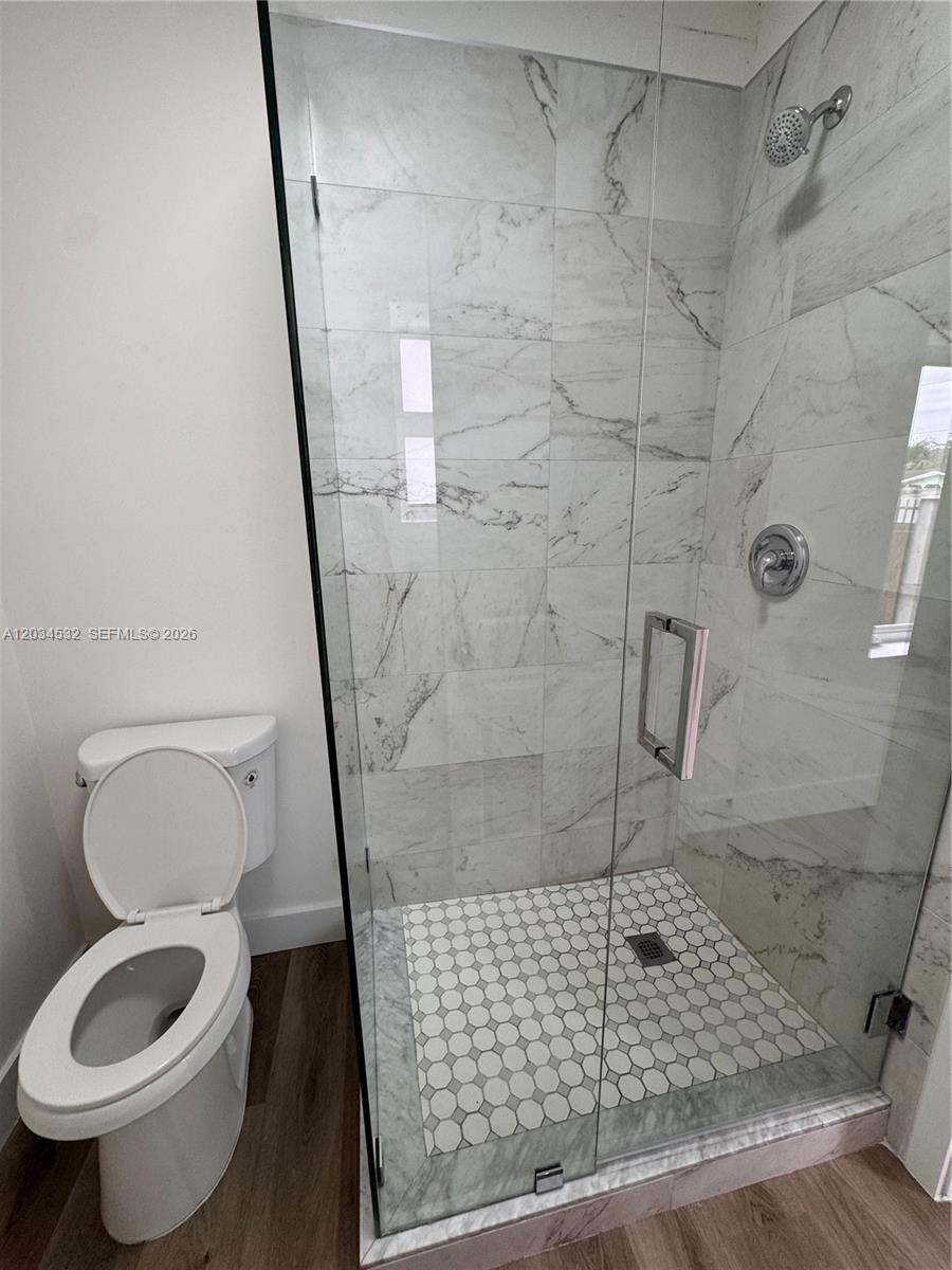 A bathroom features a glass-enclosed shower with marble-look tile and a white toilet — 2239 NW 87th St # 8, Miami FL 33147, MIAMI, FL