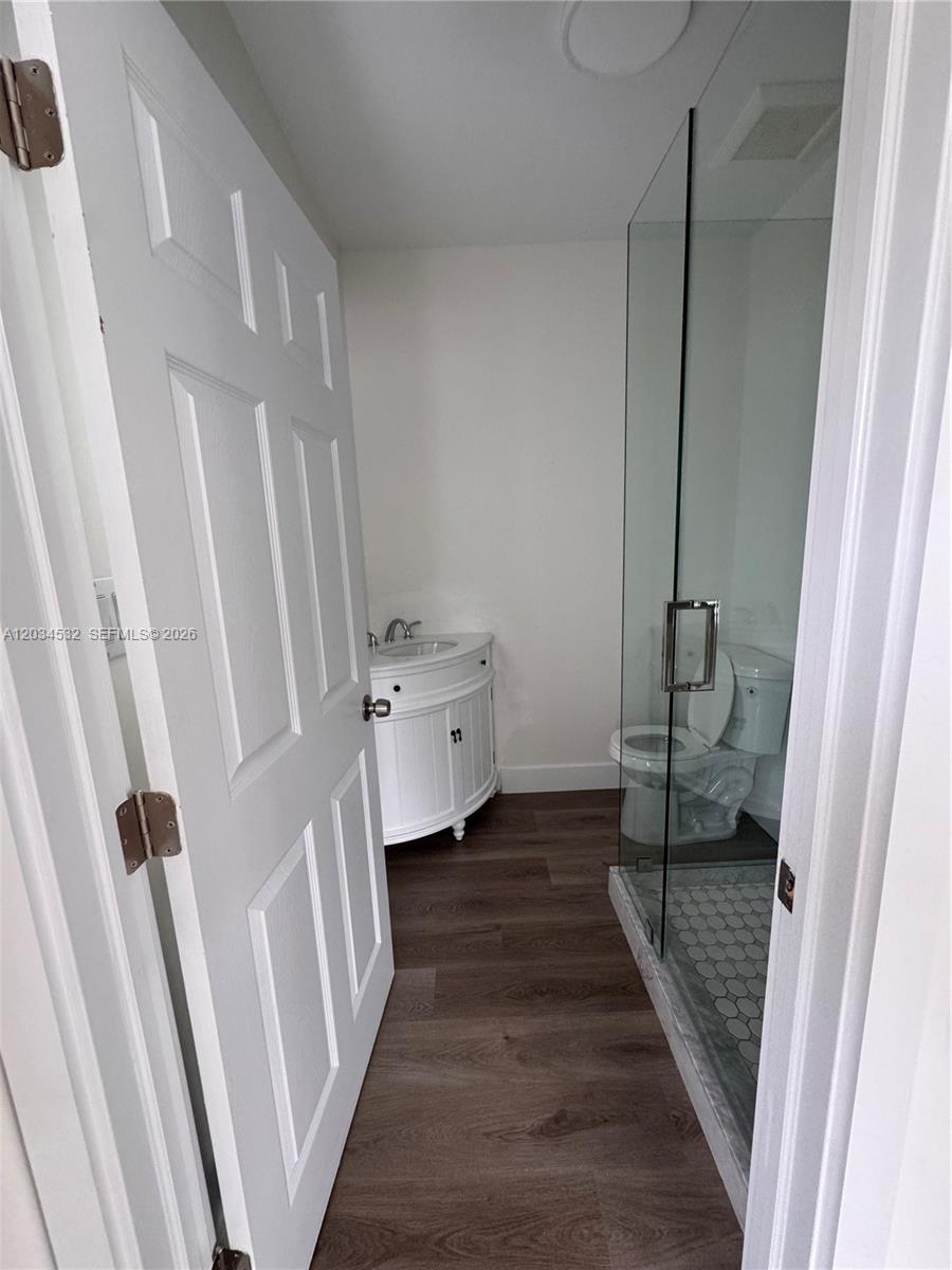 A bathroom features a white vanity, a glass-enclosed shower, and wood-look flooring — 2239 NW 87th St # 8, Miami FL 33147, MIAMI, FL