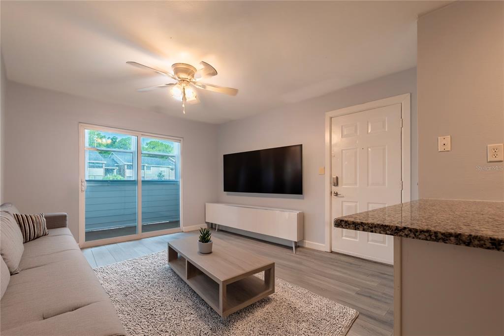 A living room features a gray sofa, a wood coffee table, and a wall-mounted television — 1400 GANDY BOULEVARD N UNIT 1010, ST PETERSBURG, FL