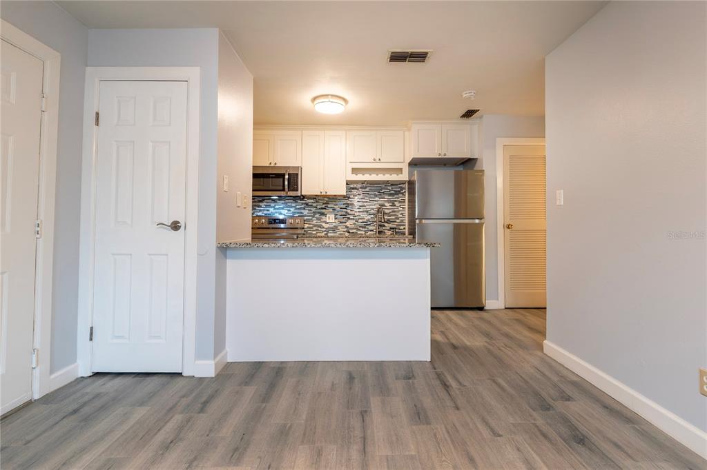 A kitchen features white cabinets, granite countertops, stainless steel appliances, and wood-look flooring — 1400 GANDY BOULEVARD N UNIT 1010, ST PETERSBURG, FL