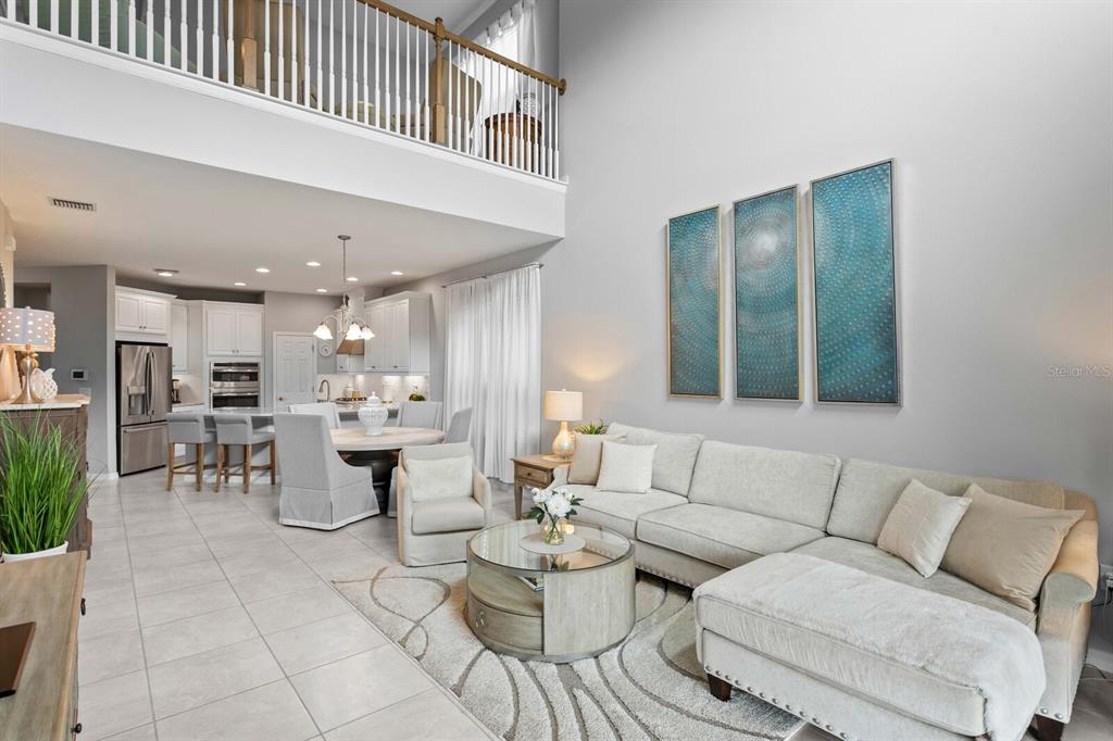 A bright, open-concept living room and dining area with high ceilings and neutral tile flooring — 8524 ARABELLA LANE, SEMINOLE, FL