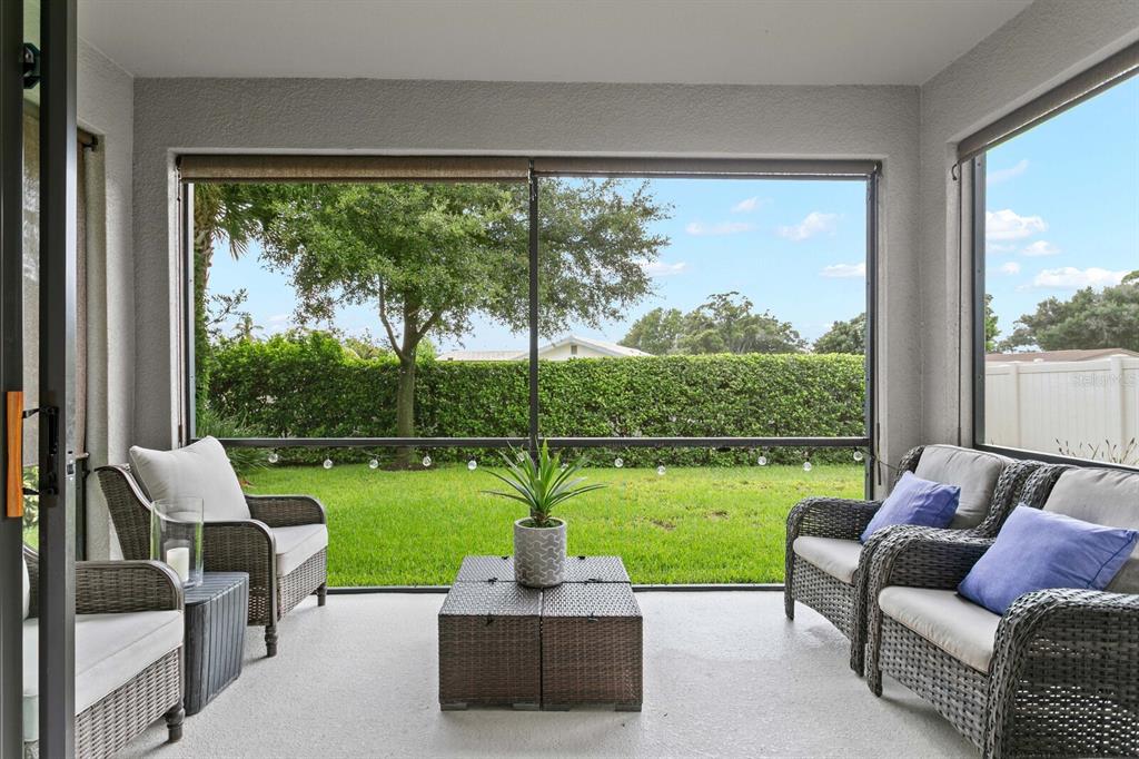A screened-in patio features wicker furniture, a central coffee table, and views of a grassy yard — 8524 ARABELLA LANE, SEMINOLE, FL
