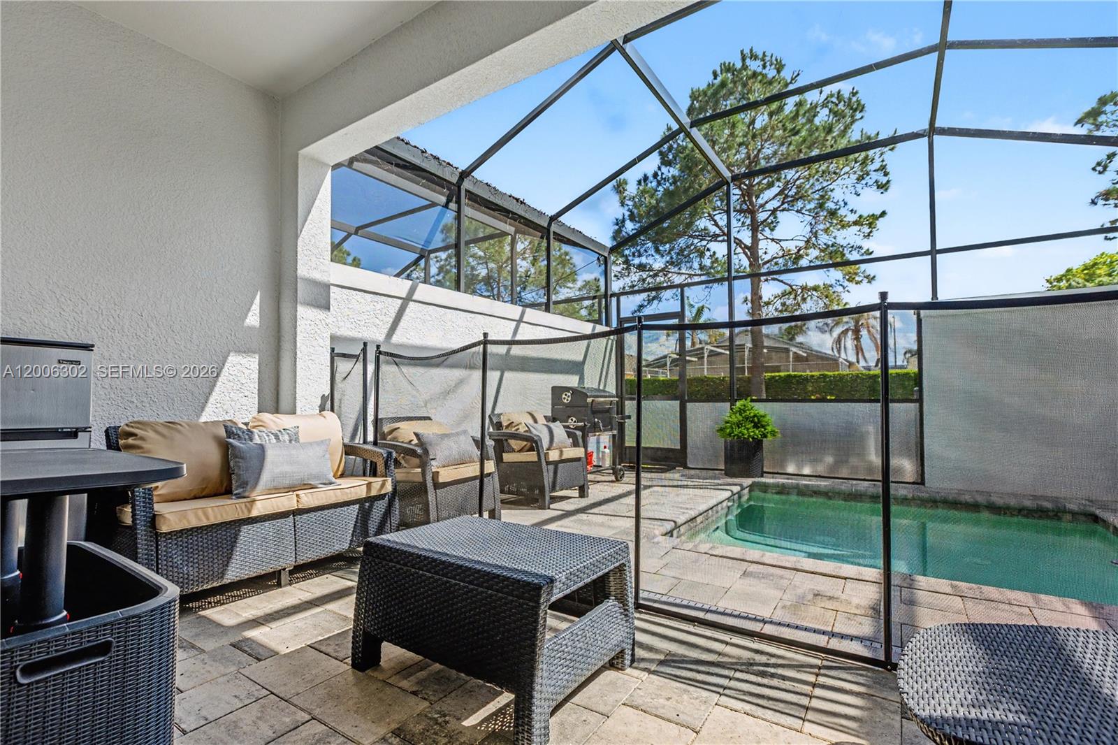 A covered patio features wicker furniture, a small pool, and a screened-in enclosure — 17416 Hidden Forest # 0, Clermont FL 34714, CLERMONT, FL