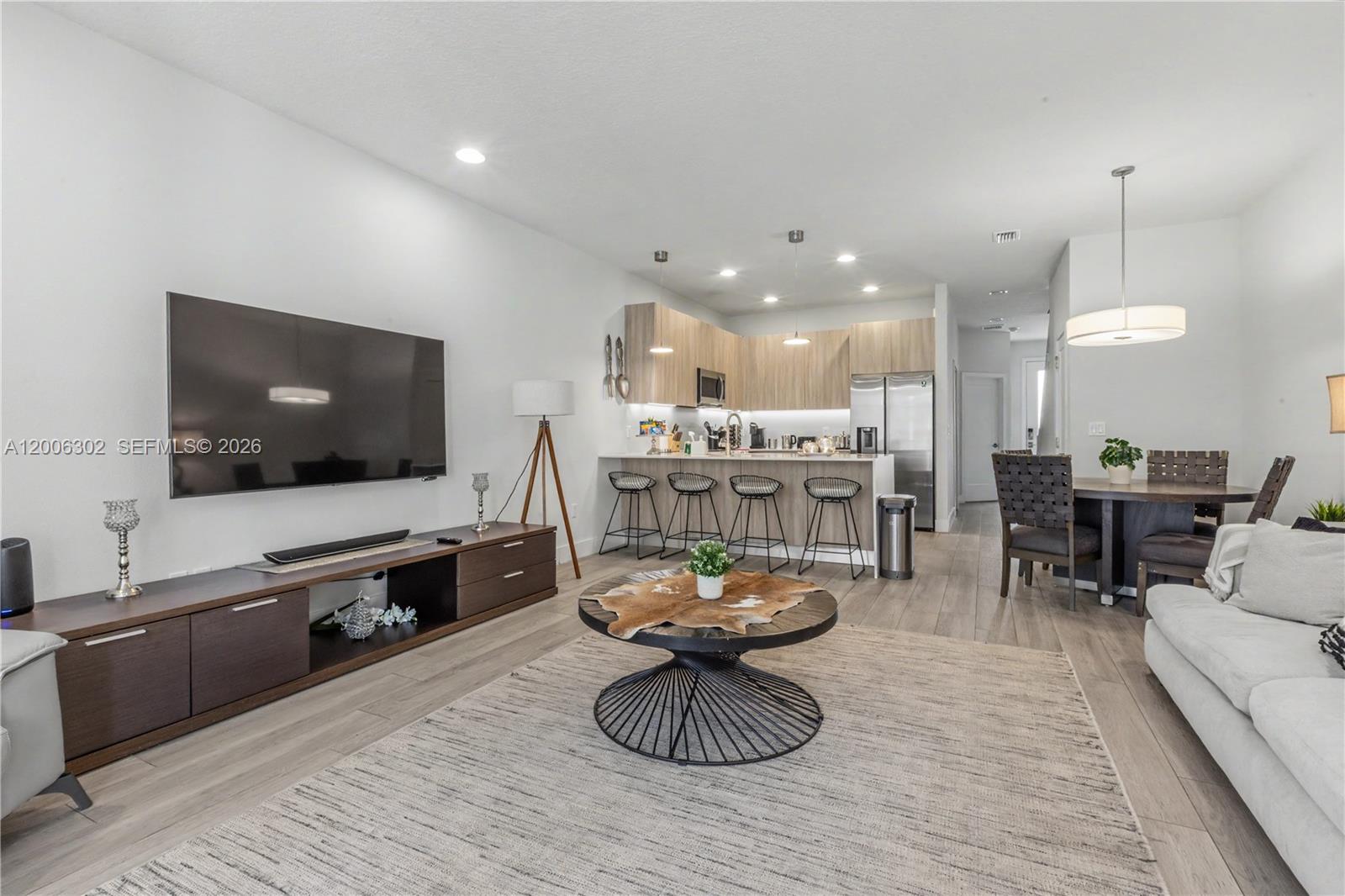 An open-concept living area features a kitchen with bar seating, a dining table, and television — 17416 Hidden Forest # 0, Clermont FL 34714, CLERMONT, FL