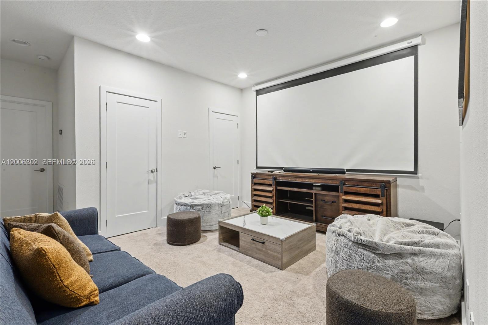 A carpeted media room features a projector screen, wooden media console, sofa, and beanbag chairs — 17416 Hidden Forest # 0, Clermont FL 34714, CLERMONT, FL